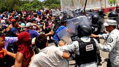 Migrantes se enfrentan con elementos de la GN...
